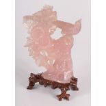 A Chinese rose quartz carving of an exotic bird perched on a tree stump, behind flowers and leaves,