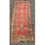 A Kurdish long rug, the madder field with eight polychrome medallions,