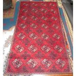 An Afghan rug, the red field with seven rows of four hexagonal medallions and rows of serrated guls,