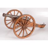 A white metal model of a cannon, on a wooden carriage, height 29.5cm, width 38cm, length 68cm.