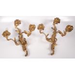 A pair of Rococo style gilt metal three branch wall lights,