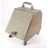 An Aesthetic Movement brass coal box, with a fluted handle above a floral decorated square panel,