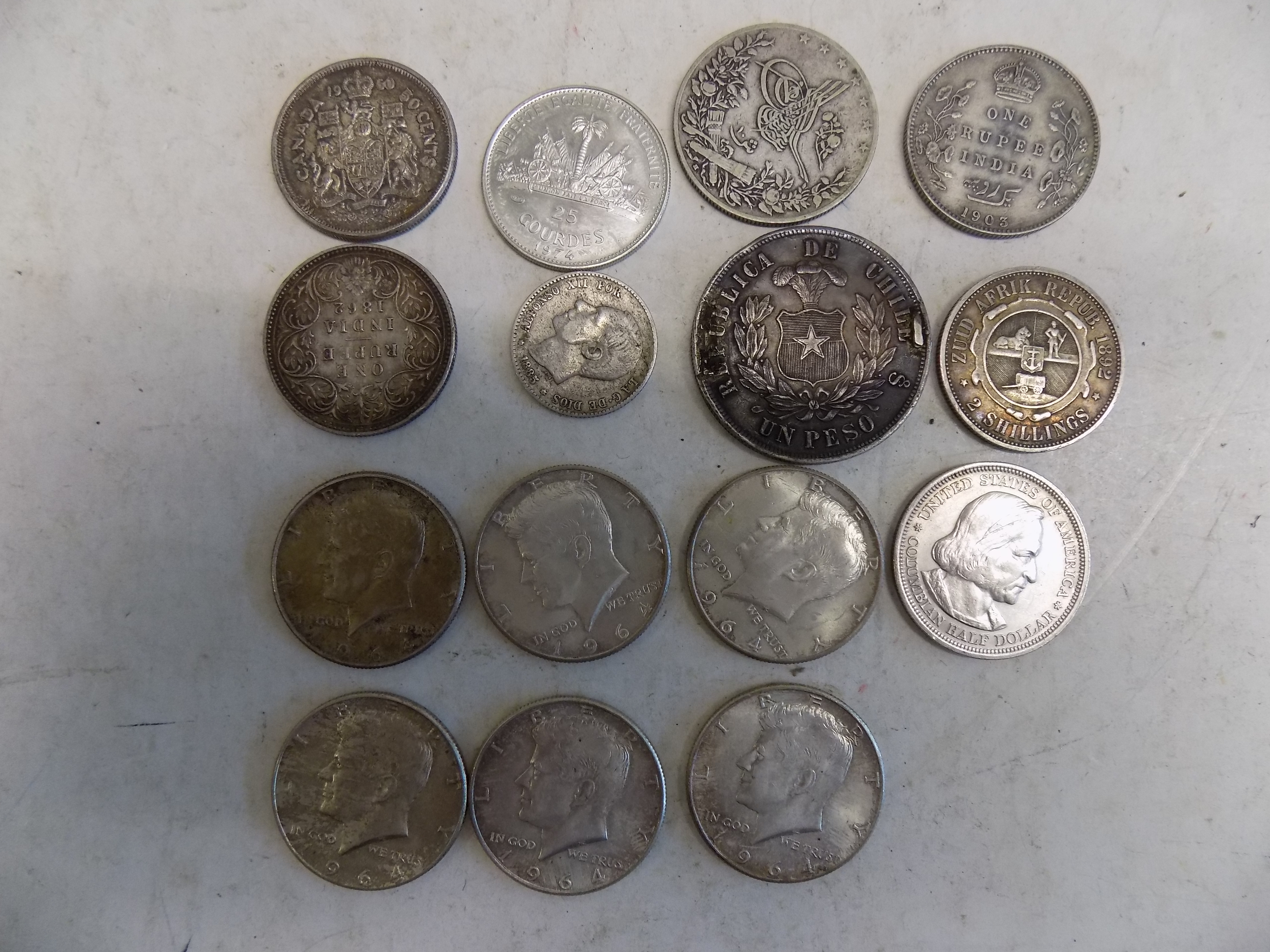 Six U.S.A. 1964 half dollars, a Chile Peso (mounted) and other silver coins.
