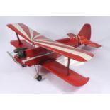 A scale model of a biplane wearing the livery of a Pitts Special aeronautical plane in red and
