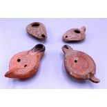 Four Roman terracotta oil lamps, lengths 12cm, 9cm, 11.5cm and 10.5cm.