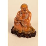 A fine Chinese coffee toned soapstone carving of a seated Lohan, possibly Handaka sonja,