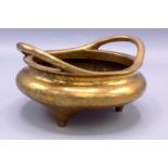 A Chinese bronze twin handled censer, 19th century, of squat form with three stile feet,