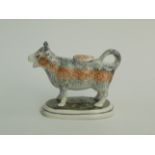 A Staffordshire pearlware cow creamer, early 19th century, standing on an oval green base,