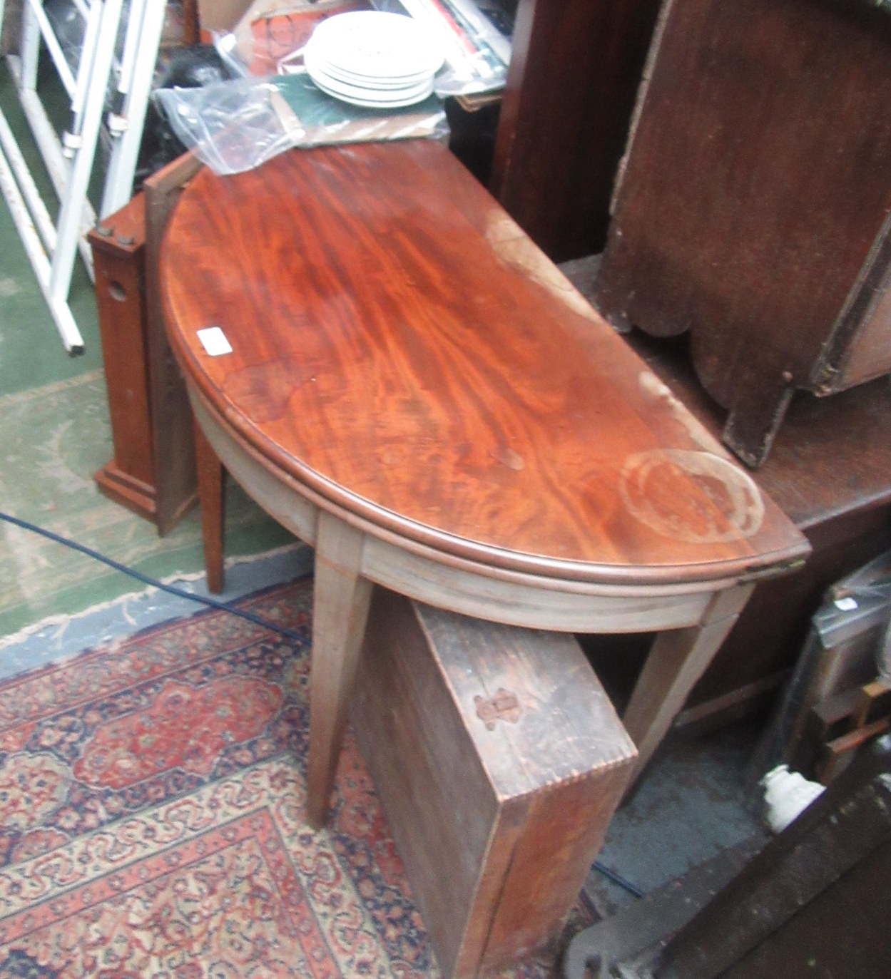 A George III mahogany demi lune card table, the moulded fold over top on square tapering legs,
