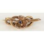 A 15ct gold clover leaf brooch set with central sapphire, the petals fringed with diamonds.