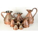 Eight copper jugs, some 19th century, largest height 39cm, smallest height 10.7cm.