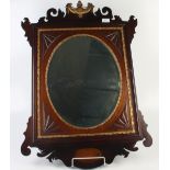 A George III style mahogany wall mirror, with an oval bevelled plate above a shell inlaid panel,
