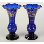 A pair of blue glass trumpet vases, early 20th century, decorated with foliage, height 29cm.