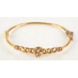 A 9ct gold bangle with a half pearl set clover leaf mount, 4.1g.