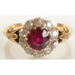 A late Victorian 18ct gold diamond and ruby flowerhead cluster ring with chased shoulders.
