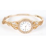 A high purity gold ladies hinged bangle wristwatch with pearl set bezel winding mechanism,