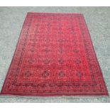 An Afghan carpet, the madder field with seven rows of four medallions, 338 x 250cm.