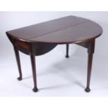 A George III mahogany drop leaf table, the oval top on circular tapering supports on pad feet,