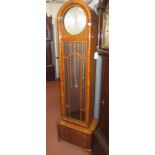 An Art Deco walnut longcase clock, with two weights and a pendulum, height 195cm, width 57cm.