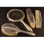 A four piece silver mounted dressing table set comprising two brushes, a hand mirror and a comb,