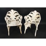 A pair of Victorian cast iron fern pattern garden seats, white painted, with wooden slat seats,