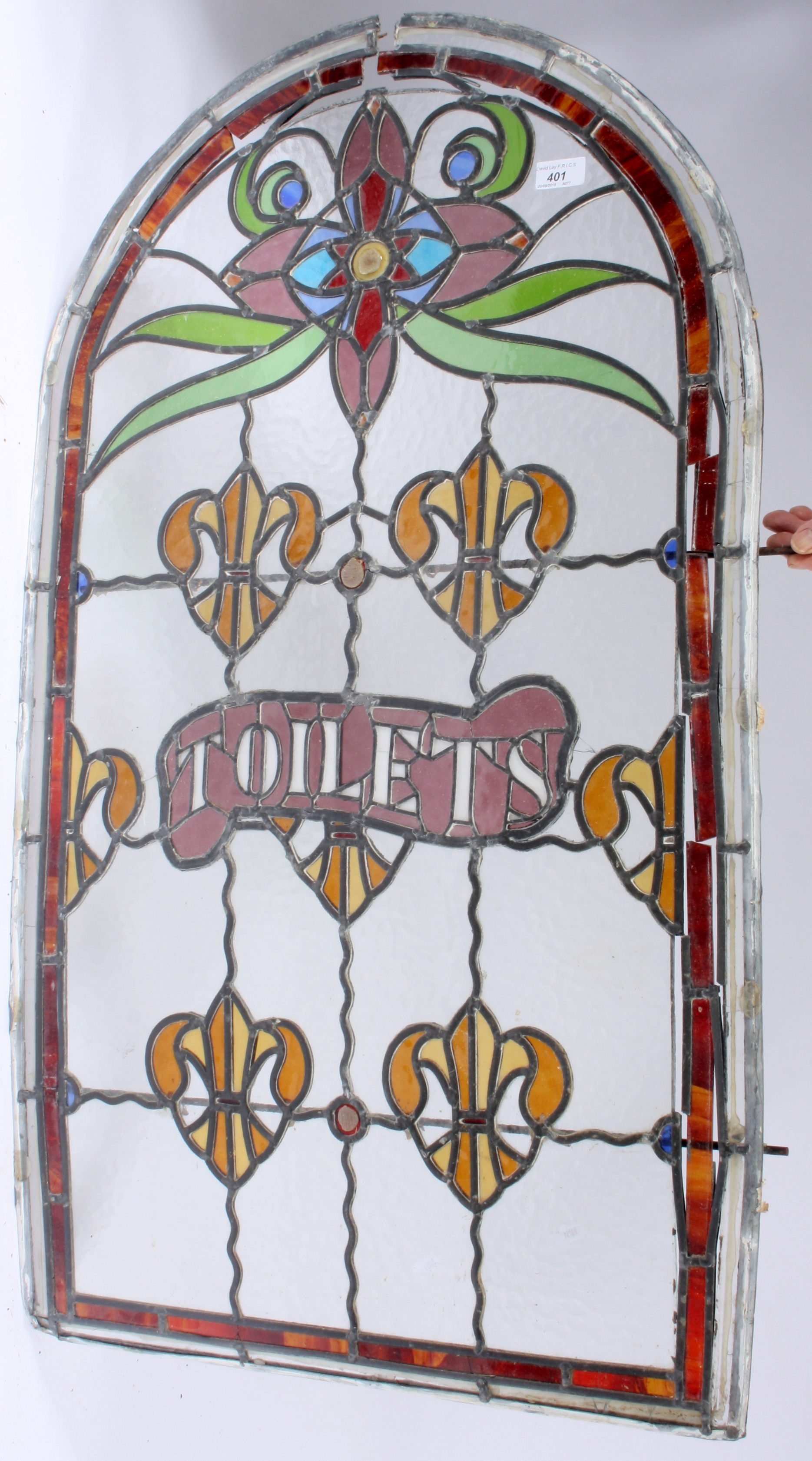 A Victorian stained glass and leaded arched window, inscribed 'Toilets', height 104cm, width 61cm.