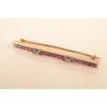 A French gold bar brooch with a central line of calibre set rubies,