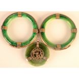 Two Chinese green stone metal mounted bangles and similar pendant.