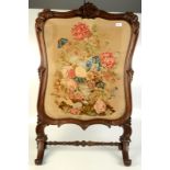A William IV rosewood and needlepoint fire screen, decorated with a vase of flowers,