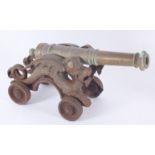 A bronze model of a cannon, on a cast iron carriage, height 22cm, length 45cm, width 16.5cm.