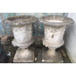A pair of composition campana garden urns, each decorated with classical scenes and masks,