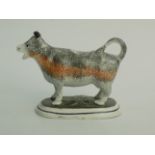 A Staffordshire pearlware cow creamer, early 19th century, standing on an oval green base,