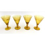 A set of four yellow stemmed glasses, decorated with grapes and vines, height 16.5cm.