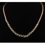 A very high purity gold necklace set with twenty four graduated square cut emeralds and separated