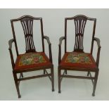 A pair of mahogany shield back open armchairs, with needlework drop in seats.