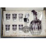 A purple flashed cut glass decanter set, cased.