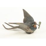A cold painted bronze model of a swallow with a shamrock in its beak, height 2.5cm, width 6.5cm.