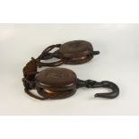 Two wooden and steel rope pulleys.