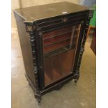 A late Victorian ebonised music cabinet, with a pair of turned columns flanking a glazed door,