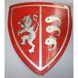 An Heraldic red painted metal shield, depicting a silver lion and three stylised fish, 58 x 55cm.