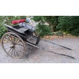 A black painted two seater horse drawn carriage, with iron spoked wheels and cast iron steps,