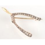 A high purity yellow and white gold diamond set wishbone brooch.