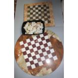 Two Carrara marble chess boards, one diameter 60cm, the other 42 x 42cm and a chess set.