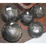 Five black painted cast iron cannonballs.