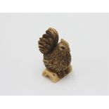 A bone netsuke carved as a hen, early 20th century, height 4.3cm, width 2.4cm.