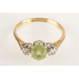 An 18ct yellow gold ring set a peridot flanked by diamonds.