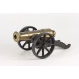 A bronze model cannon, on a cast iron carriage, length of cannon 25cm.