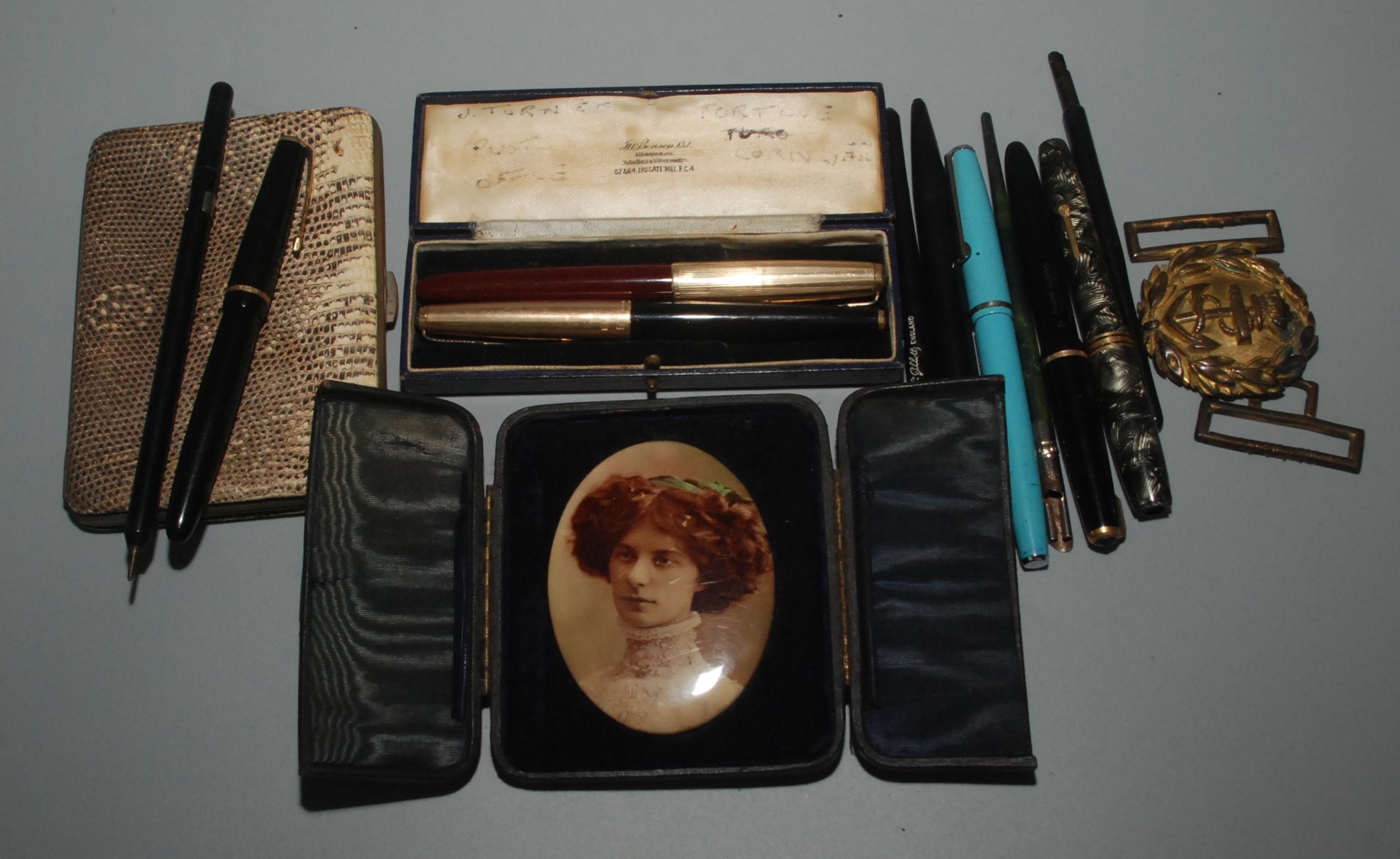 Fountain and other pens, a portrait, a naval two part buckle and a snake skin purse.