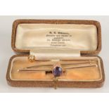 A gold stickpin set a diamond and a 15ct gold bar brooch set an amethyst.