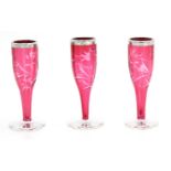 A set of three miniature cut cranberry glass vases,